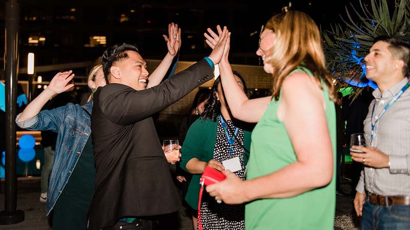 ServiceMax employees giving one another high-fives at a party